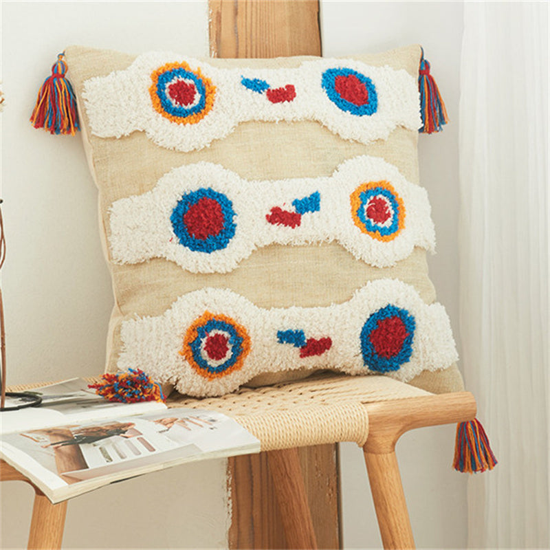 Tufted boho pillow cover with playful circle motifs on a wooden bench