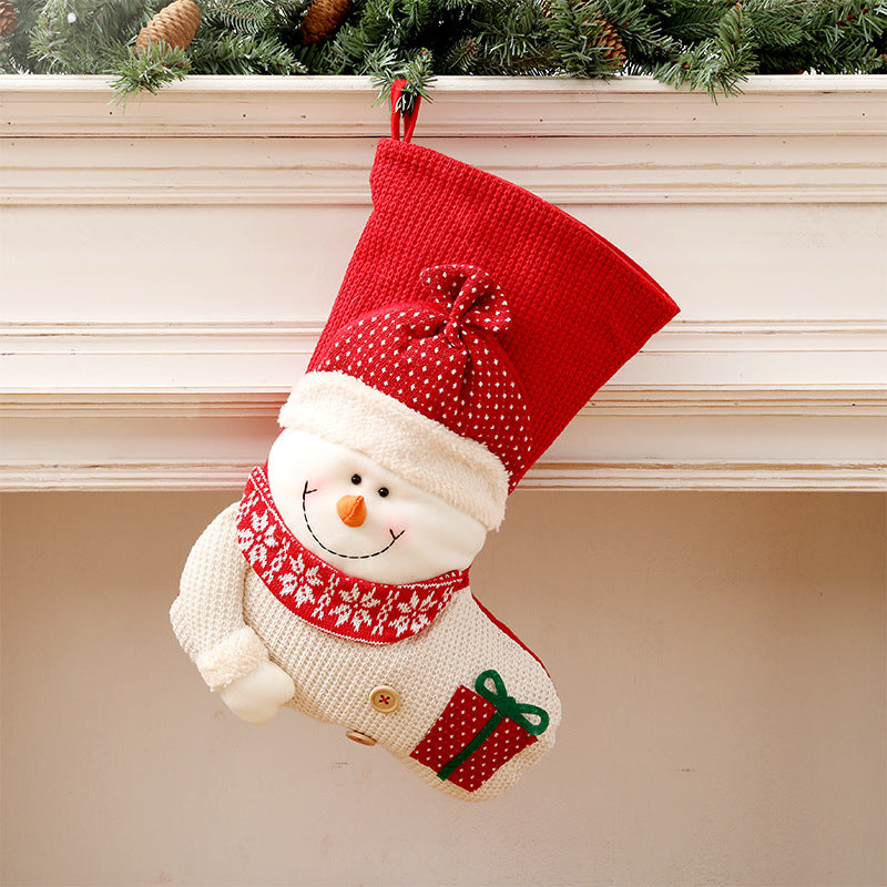 Knit snowman stocking with red hat hanging by the fireplace