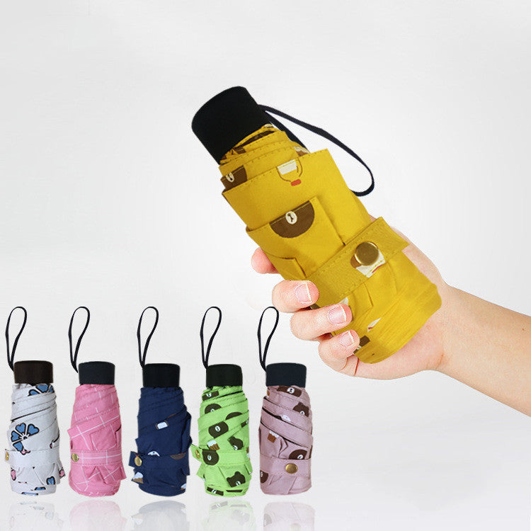 Hand holding pocket sized capsule umbrellas in assorted colors