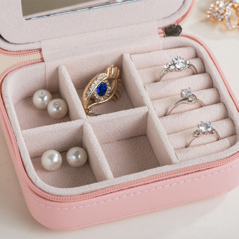 Open pink travel jewelry case filled with rings and earrings