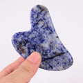 Hand holding a heart shaped blue jade gua sha stone