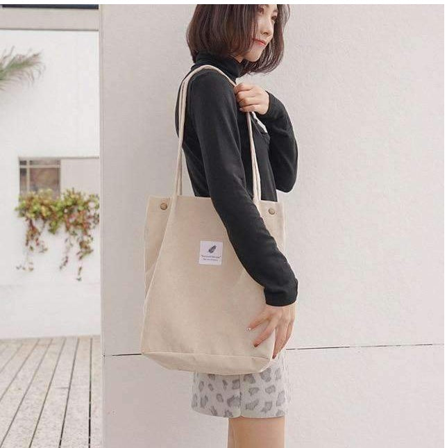 Beige corduroy tote bag carried on the shoulder outdoors