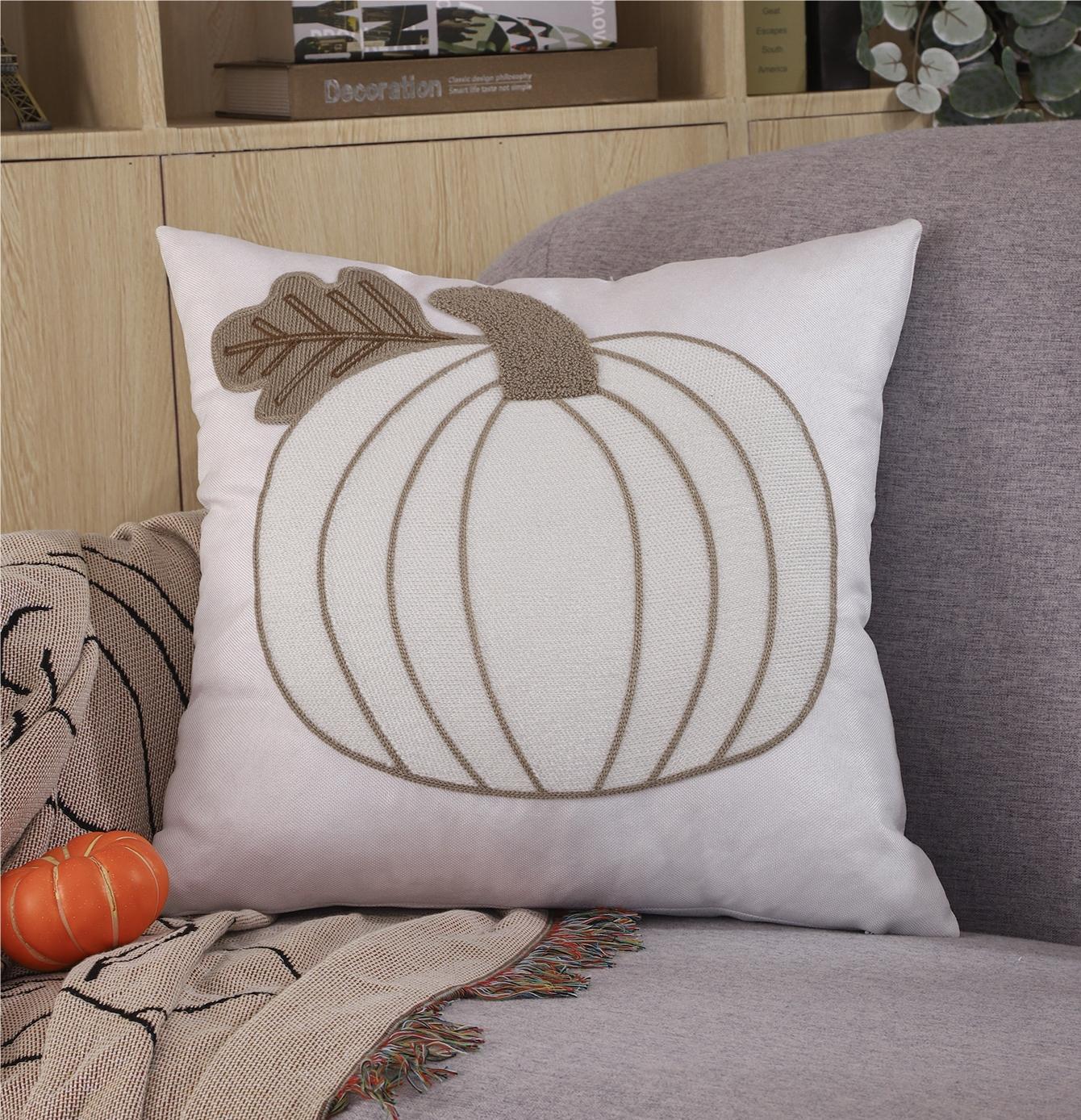 Embroidered pumpkin pillow styled on a bed for fall
