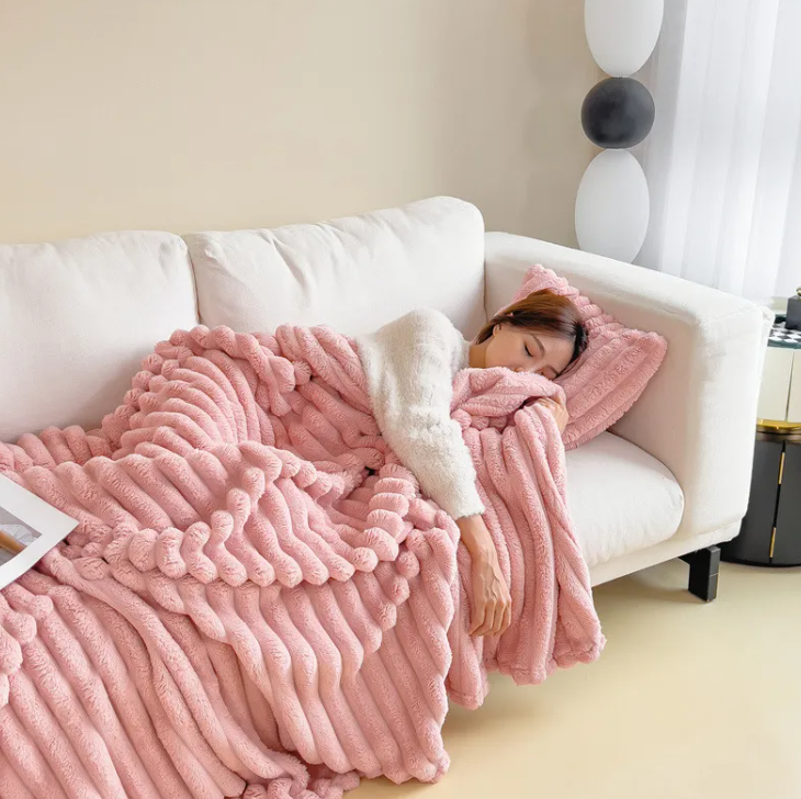 Pink ribbed plush blanket draped over a cozy couch