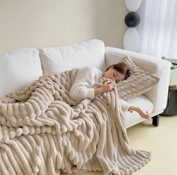 Khaki ribbed plush blanket covering a napping woman on a couch