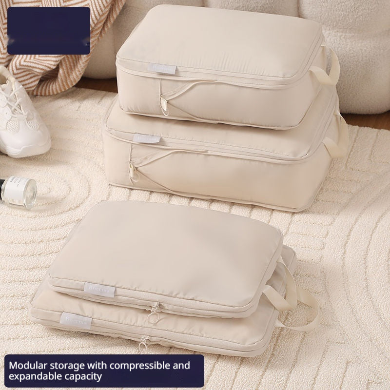 Traveler unzipping a beige packing cube from an organized suitcase