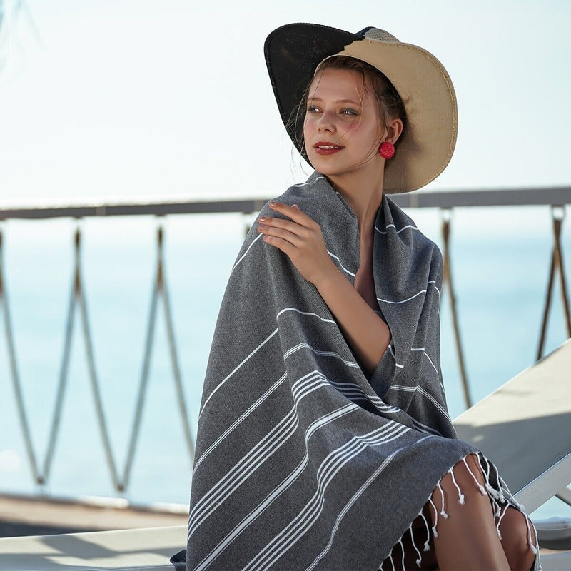 Woman relaxed in a striped Turkish beach towel by the sea