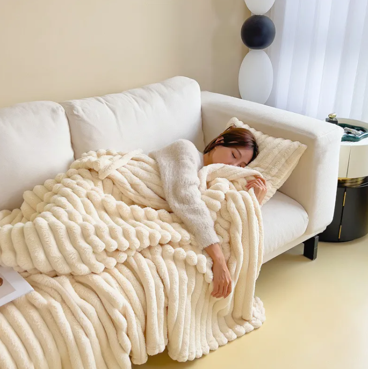 Milky white ribbed plush blanket draped over a sofa