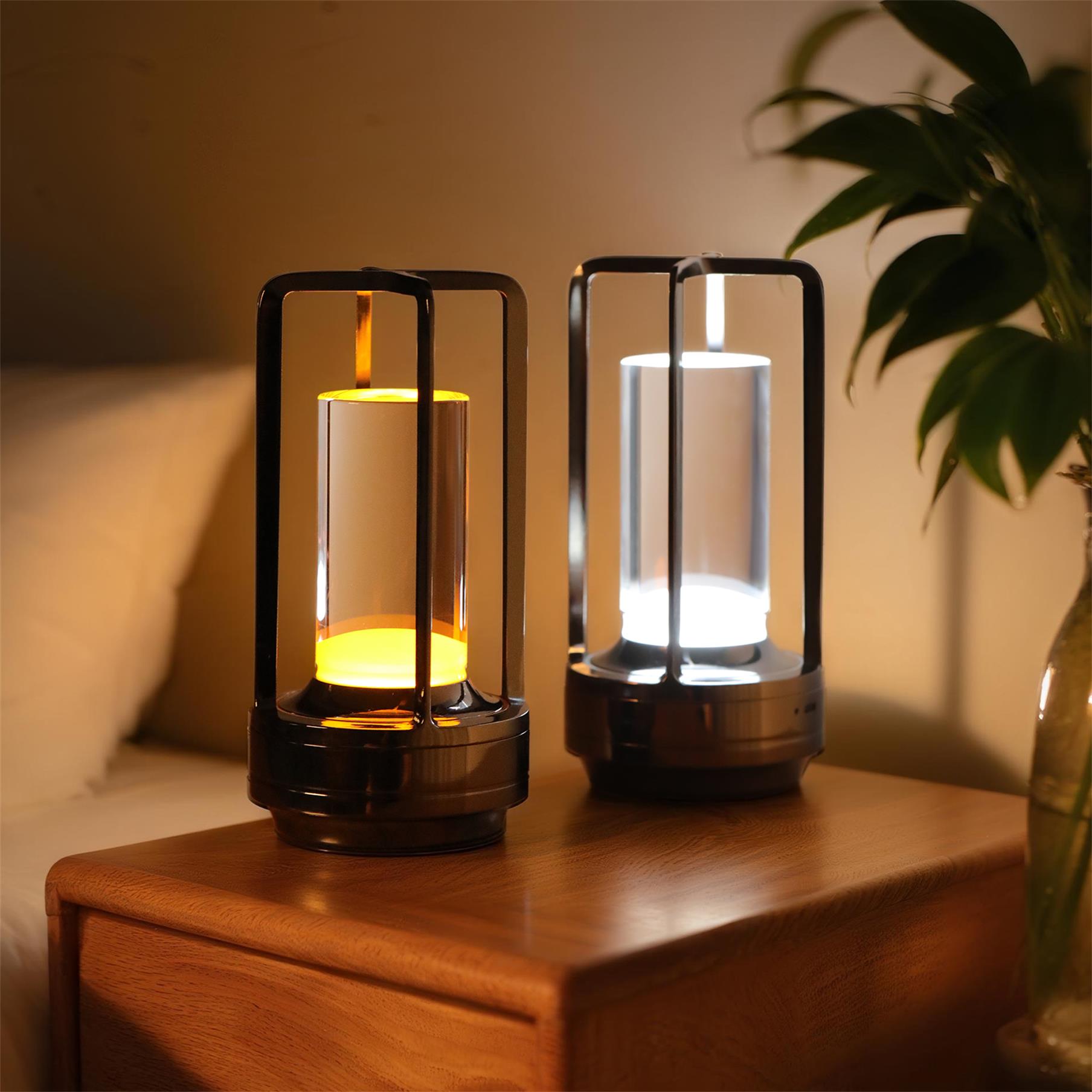 Two cordless aluminum accent lamps glowing warm on a wooden nightstand