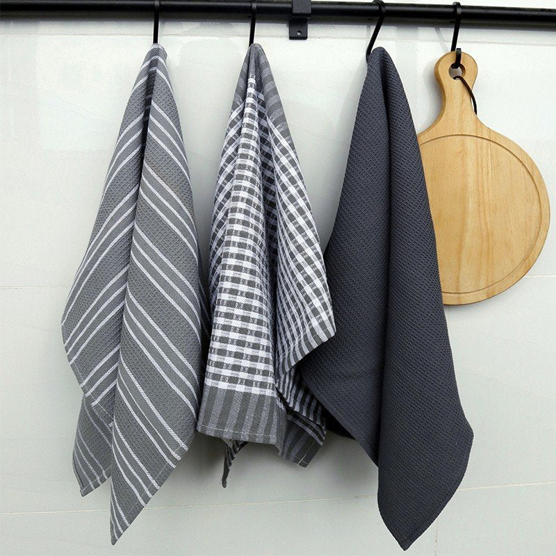 Striped tea towels hanging in a kitchen beside a cutting board