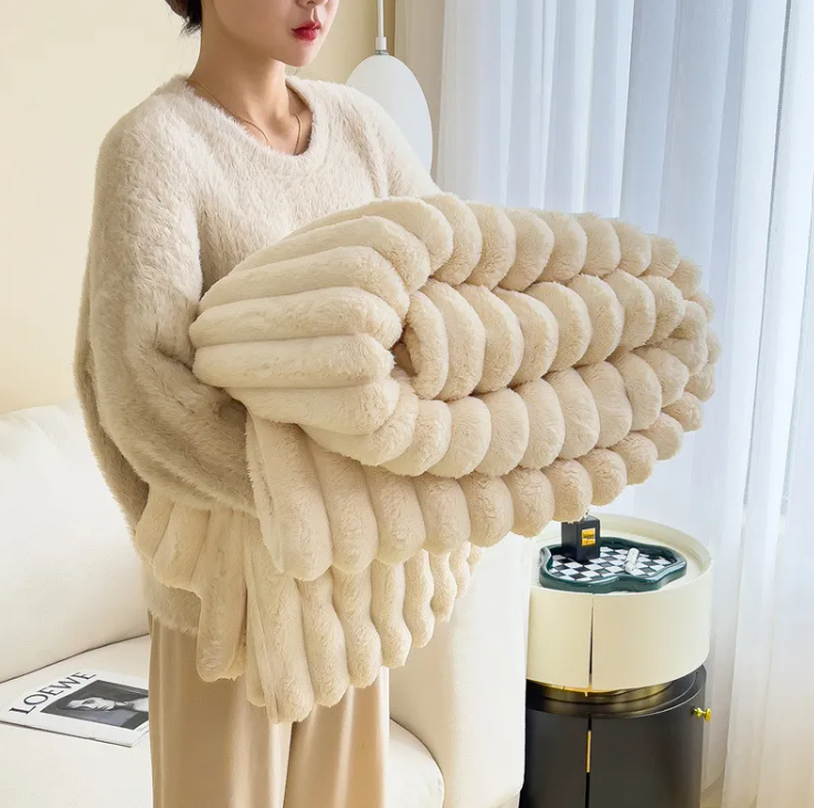 Holding the thick ribbed plush blanket, showing its cozy fluffy texture