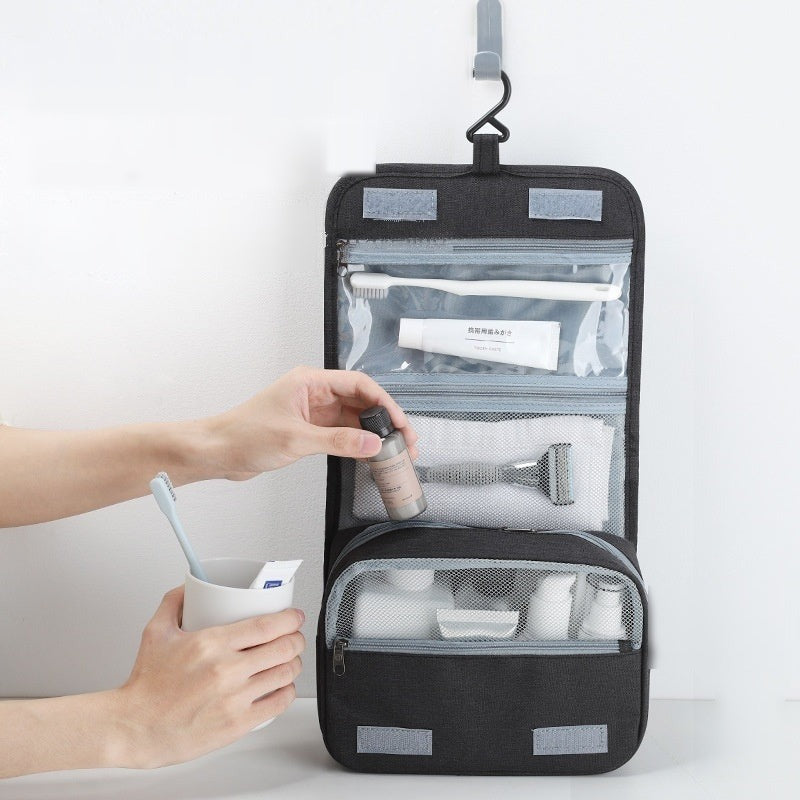 Hands loading toiletries into a black hanging toiletry bag with clear pockets