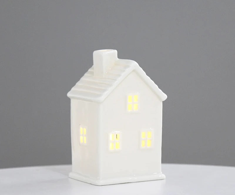 White ceramic cottage tea light house with chimney, lit warmly