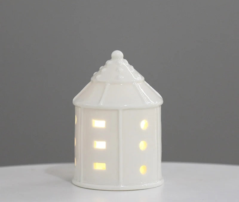 White ceramic round tower tea light house with scalloped roof, glowing